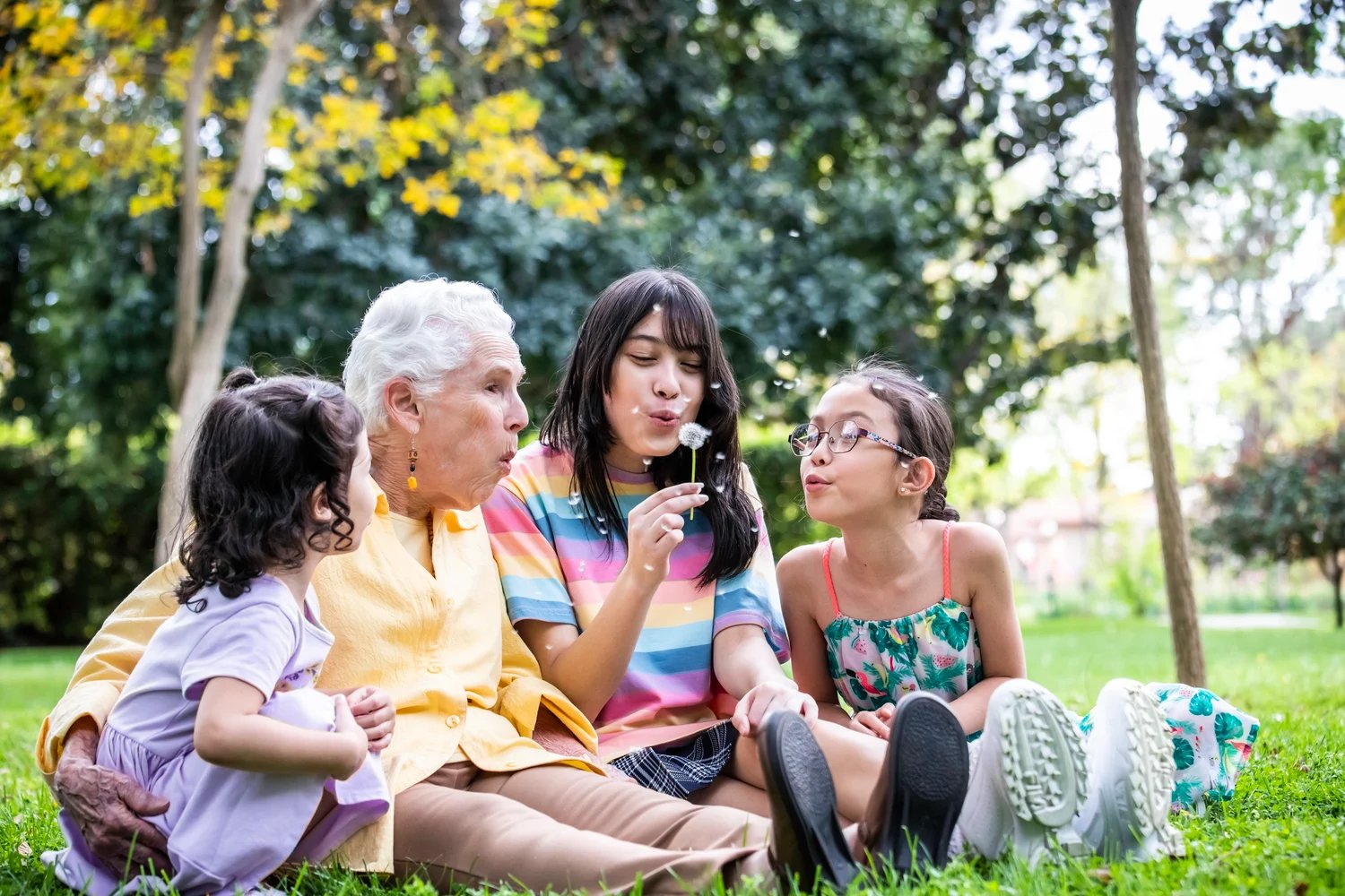 Grandma blowing dandelion with grandchildren